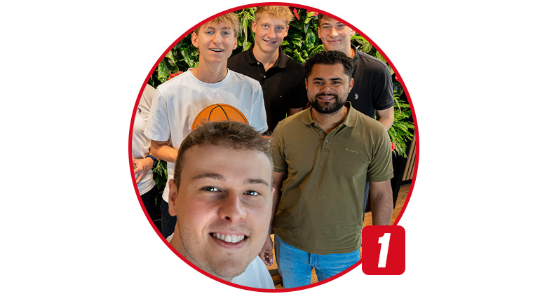 Ein junger Mann macht ein Selfie mit vier weiteren Personen vor einer grünen Pflanzenwand, einer hält einen Basketball.